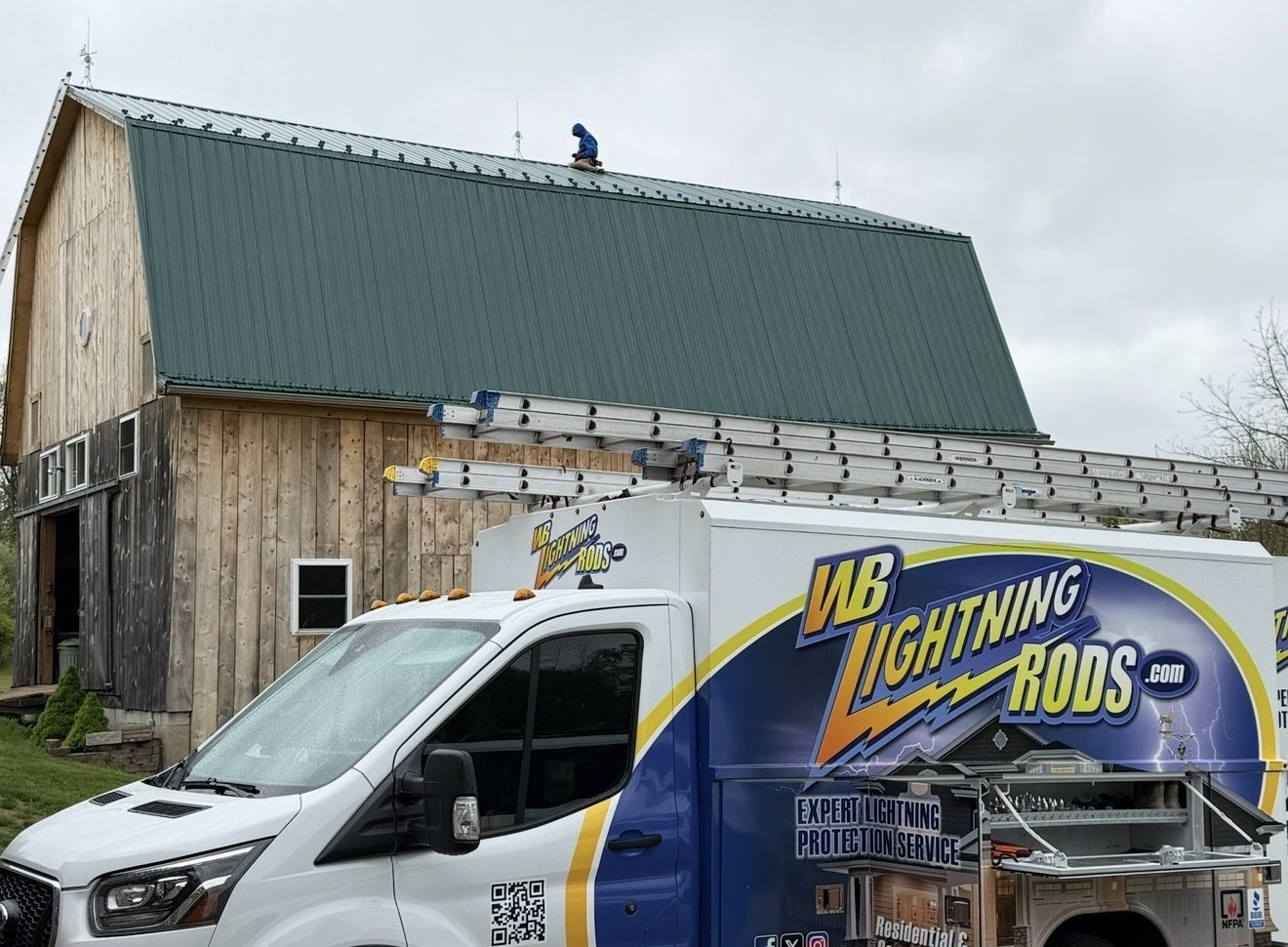WB Lightning Rods van in front of a large gambrel-roof barn on a working farm