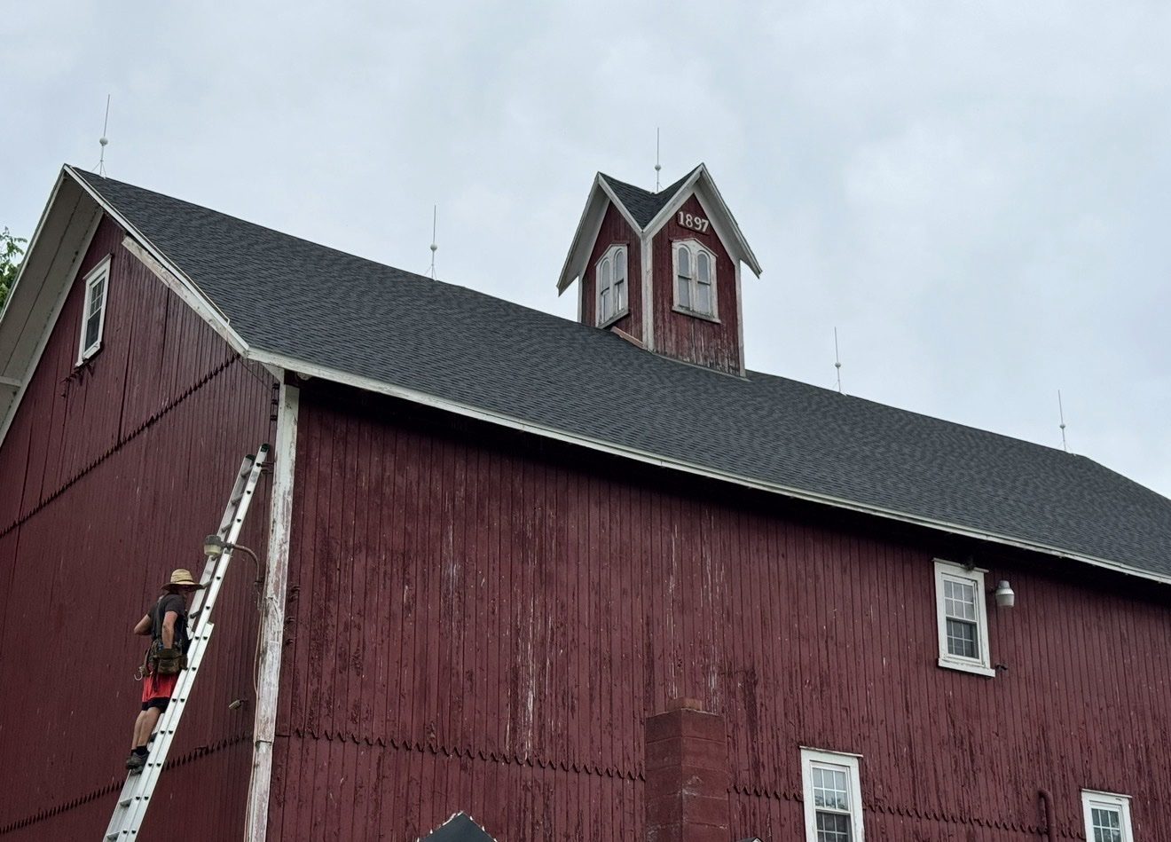 Historic red bank barn with the WB Lightning Rods van alongside and farmland behind